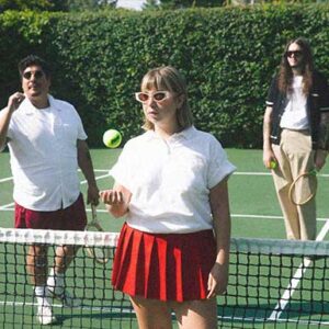 Die Band Beach Bunny steht im Tennisoutfit und mit Sonnenbrille auf einem Tennisplatz