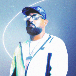 Porträt von Caney030: Er steht vor einem blauen Hintergrund, Lichtreflexe spiegeln sich in seiner Brille.