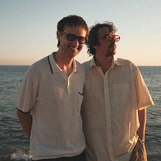 Die Band Shouse steht am Strand mit dem Rücken zum Meer
