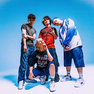 Die Band steht vor einem blau-weißen Hintergrund